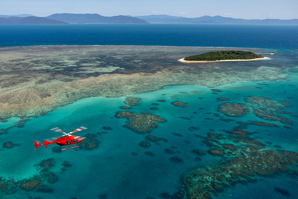 Helicopter flying over coral reefs and turquoise waters near Green Island on the Great Barrier Reef